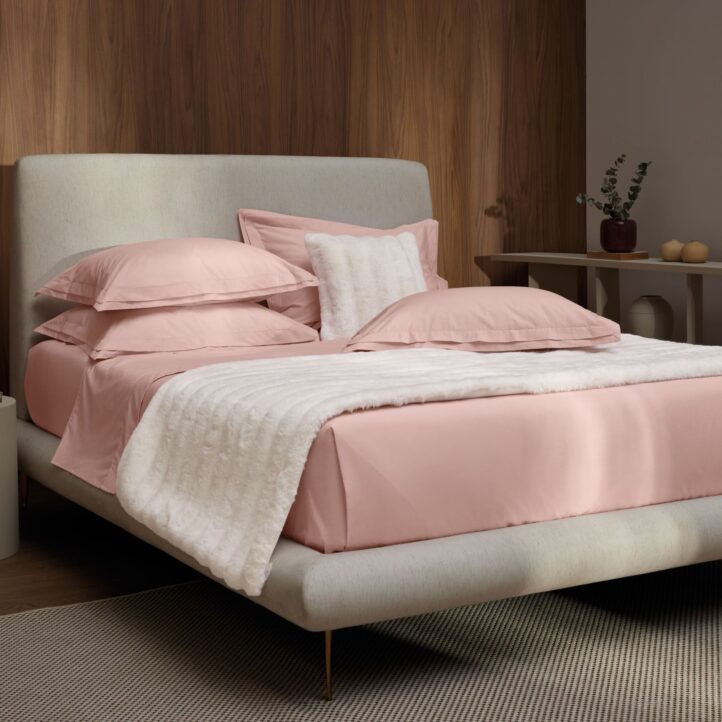 Foto ambientada de cama tamanho queen com jogo de cama de algodão na cor rosa soft com peseira na cor branca